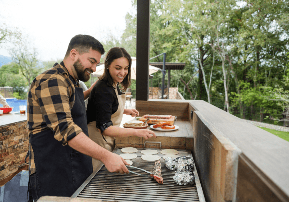 Couple cooking in outdoor kitchen in backyard.