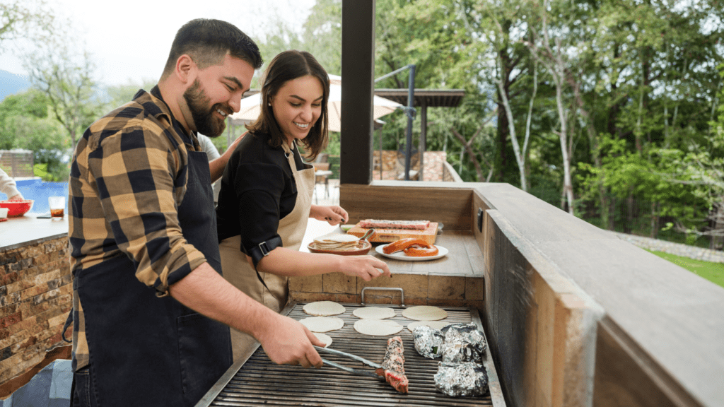 Couple cooking together in their outdoor kitchen. 