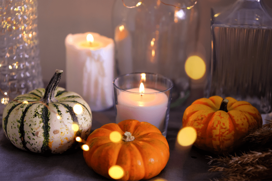 Gourds and candles on a fireplace mantel for fall.