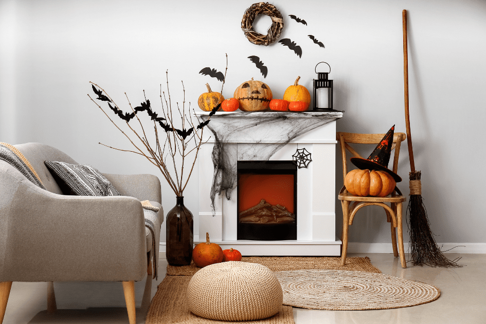 Pumpkin decor on a white fireplace with bats and witch's broom 