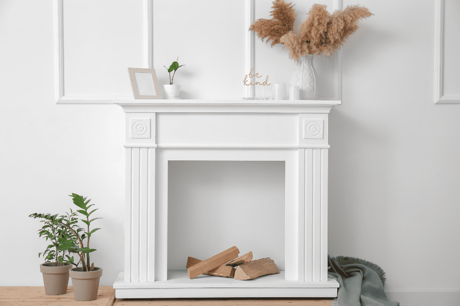 White fireplace with fall décor including feathers and picture frames 