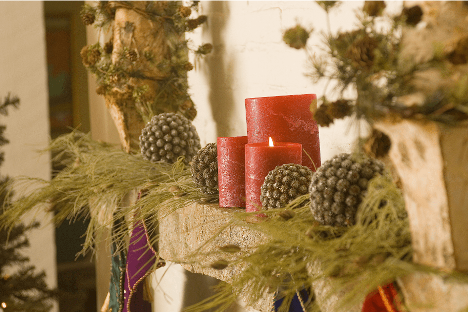 Pine cones, red candles, rustic décor on a fireplace 