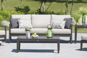 Stock image of a Ratana patio furniture set that is dark brown with off white cushions and grey and green accents throughout.