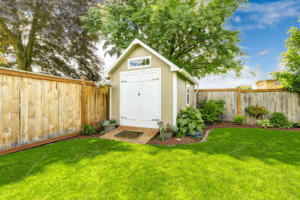 Sage green storage against the back left corner of a backyard