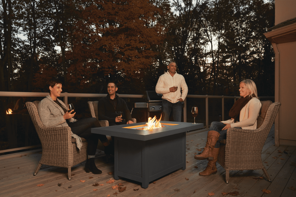A group of friends relaxing on a patio, gathered around an evening fire