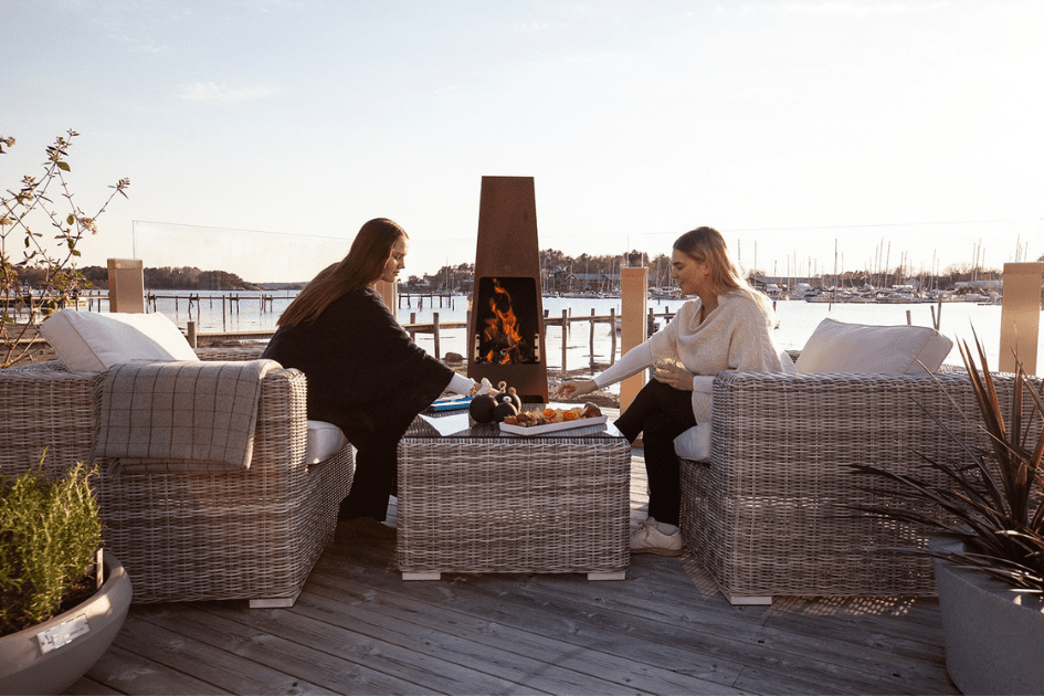 Sisters sit across from each other on a backyard patio overlooking the water