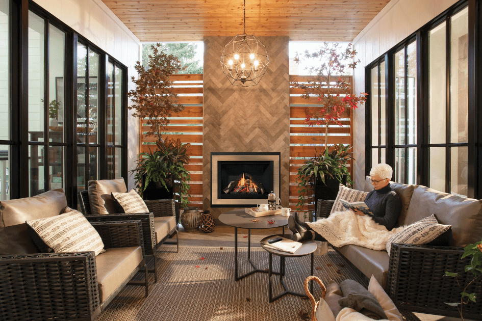 A woman sits in her reading room with a fireplace in the background, cozy under a blanket.